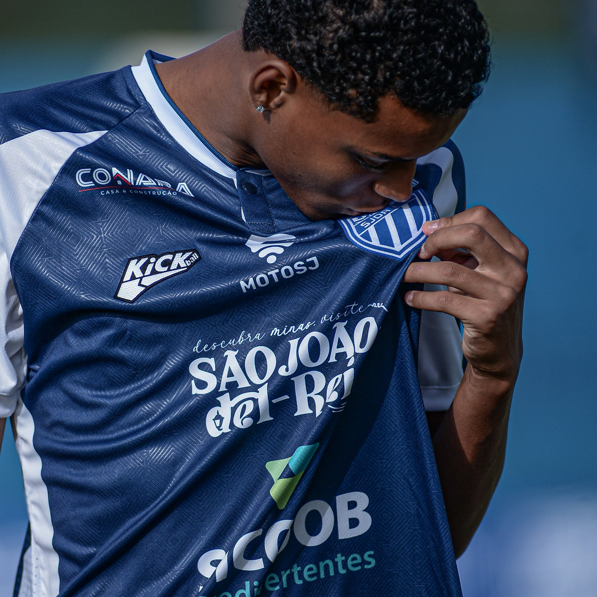 Jogador beijando o escudo do SJDR E.C. com a camisa mandante